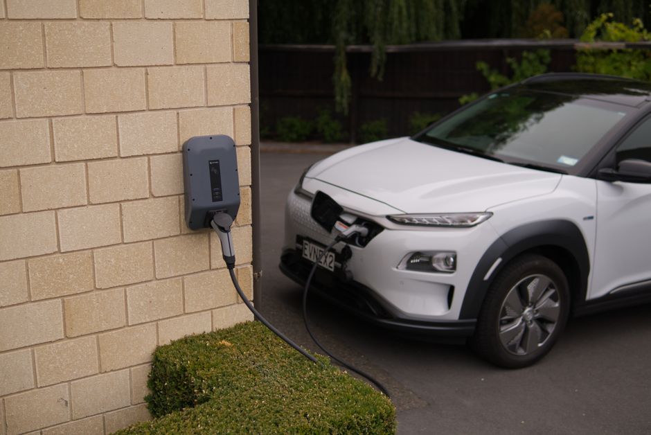 A white electric car charging at a station in Christchurch, New Zealand.