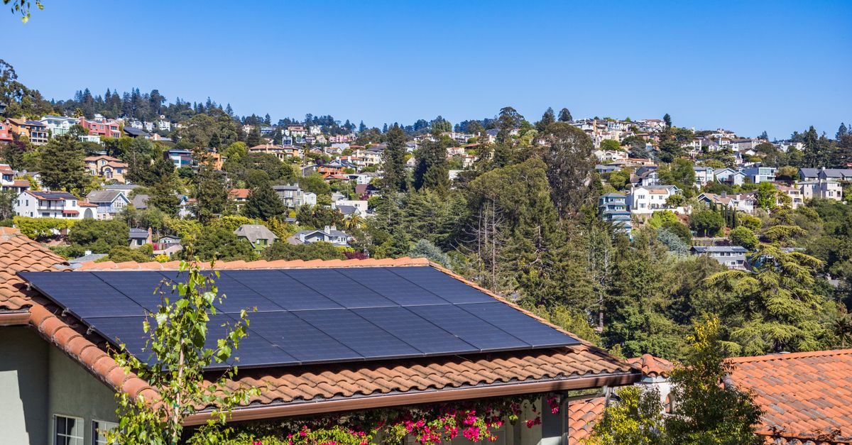 A suburban home with rooftop solar panels and leafy green surrounds