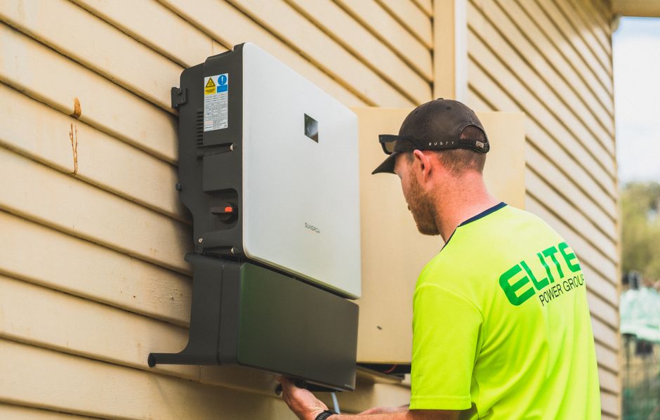 A skilled technician working on the installation of a solar inverter system outdoors.