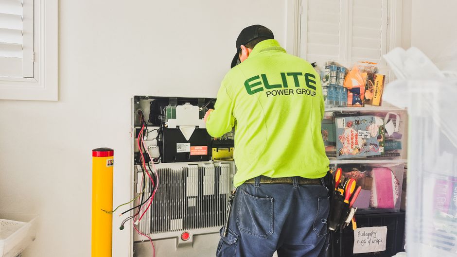 A technician installing a home solar inverter system indoors.