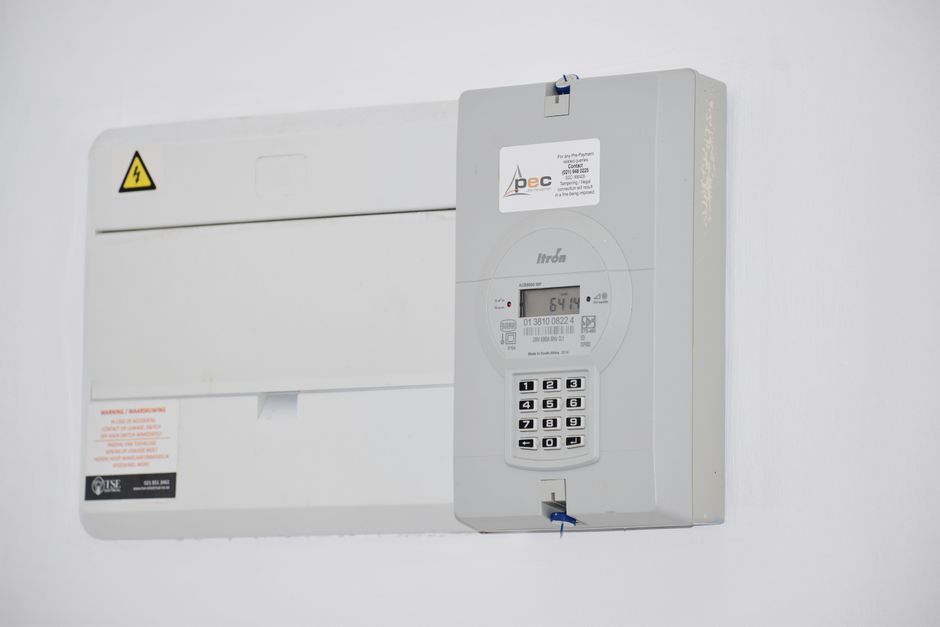 Electrical meter and fuse box on a white wall, for energy monitoring or billing.