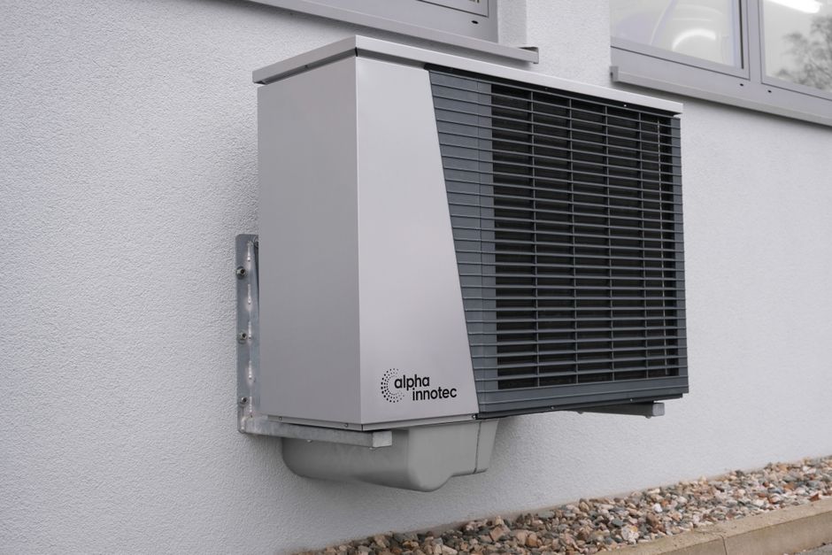 Outdoor heat pump unit mounted on a residential building exterior.