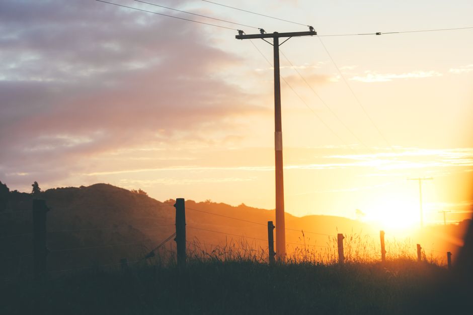 Breathtaking sunset over a peaceful rural landscape with utility poles and rolling hills.
